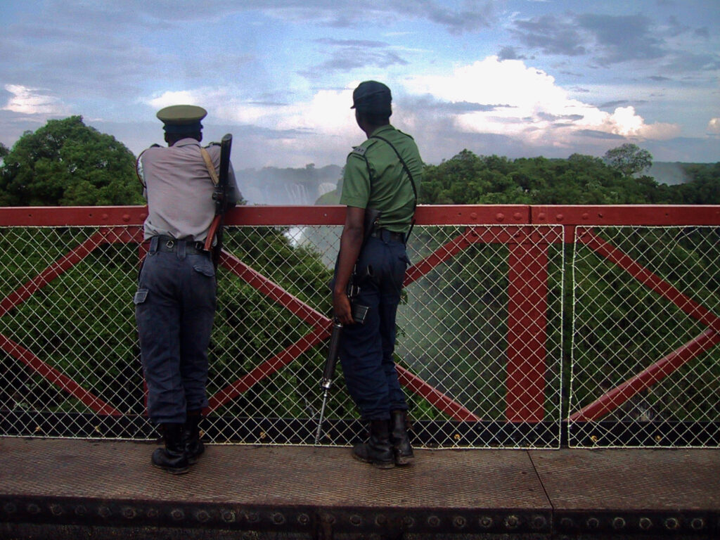 Guards watching Victoria Falls from border bridge