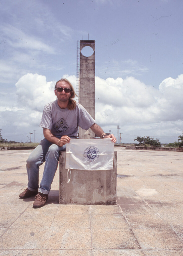 Peter and the Australian Geographic flag at the Equator Monument in Macapa (Peter Moore)